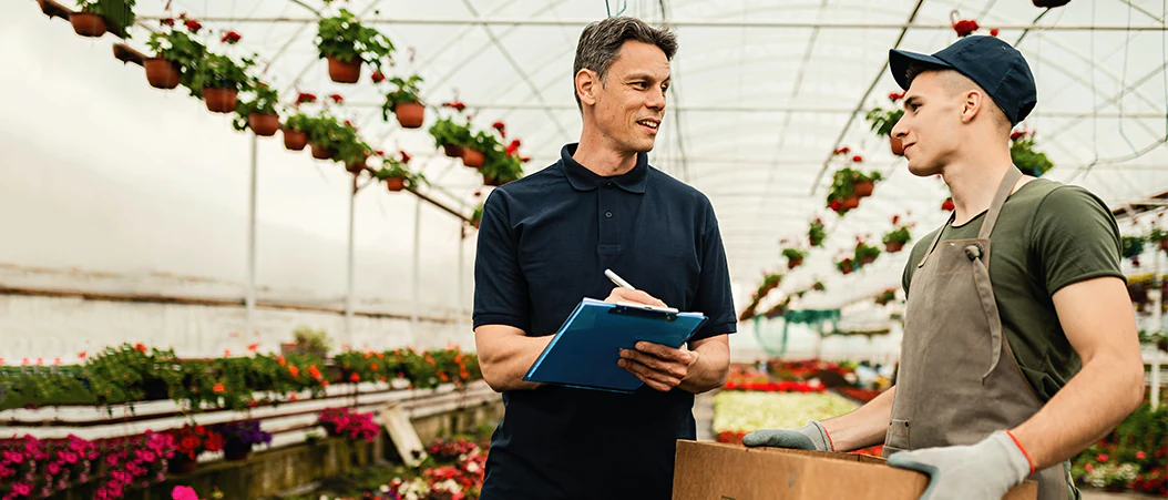 A banner image showing two workers communicating inside a greenhouse.